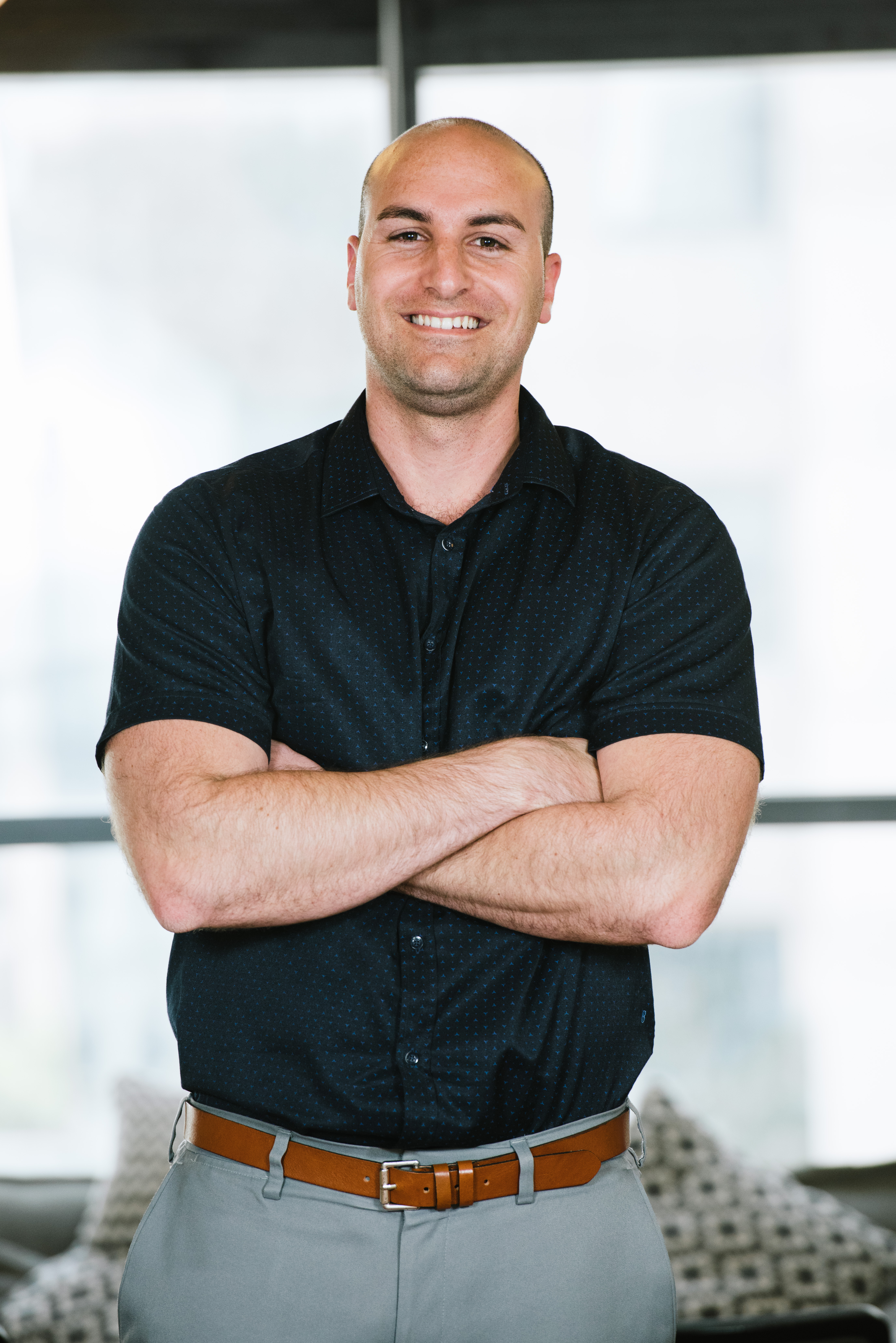 Tomer Aharon smiling with his arms folded