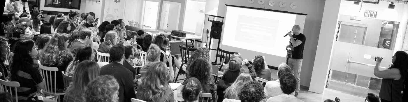 Tomer Aharon speaking to an audience at a packed event